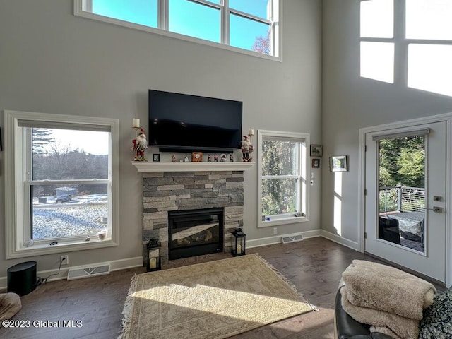 living area with a towering ceiling, a fireplace, wood finished floors, and visible vents