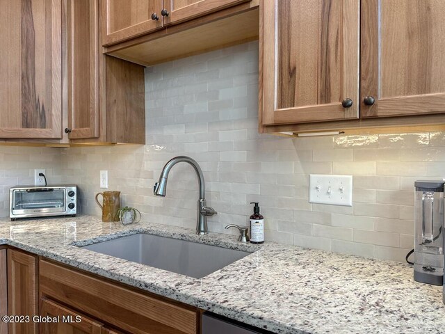 kitchen featuring sink, light stone countertops, and backsplash