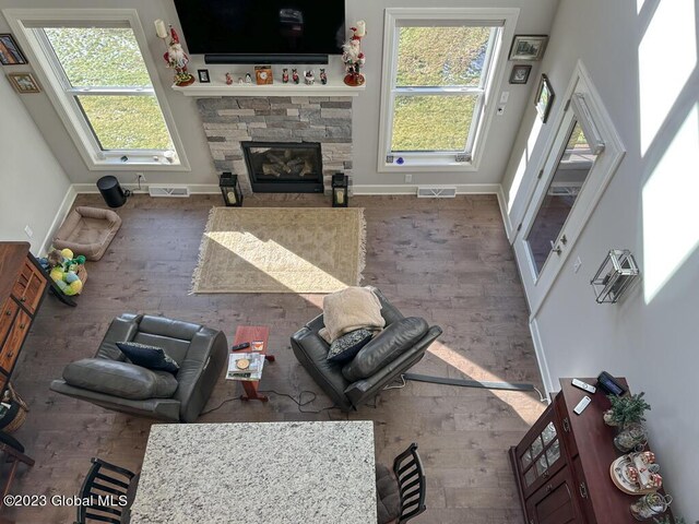 living room with a stone fireplace, hardwood / wood-style floors, and a towering ceiling