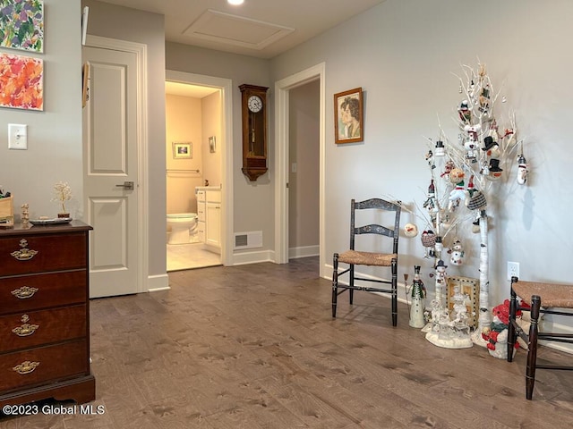 hallway featuring dark wood-style floors, baseboards, visible vents, and attic access