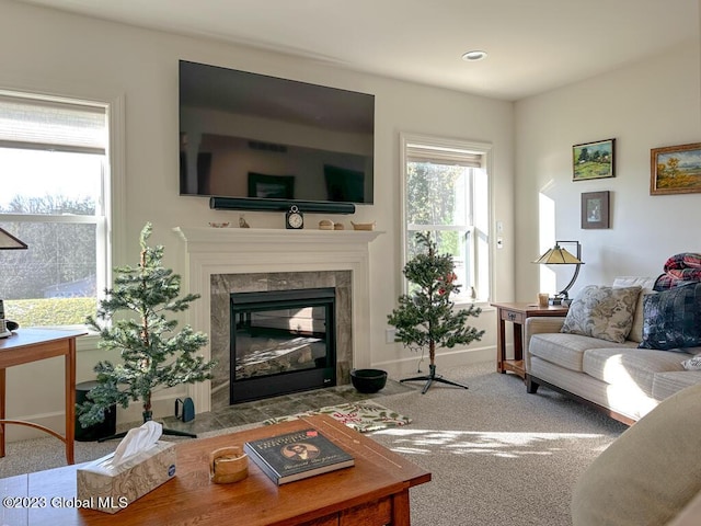 living room with a high end fireplace, baseboards, and carpet