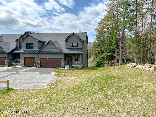 view of front of home with a garage, stone siding, aphalt driveway, and a front lawn