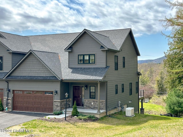 view of front of house with a garage, covered porch, a front lawn, and cooling unit