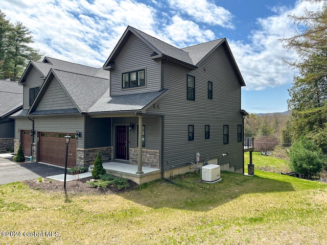 view of front of house featuring a garage, a front yard, and central AC unit