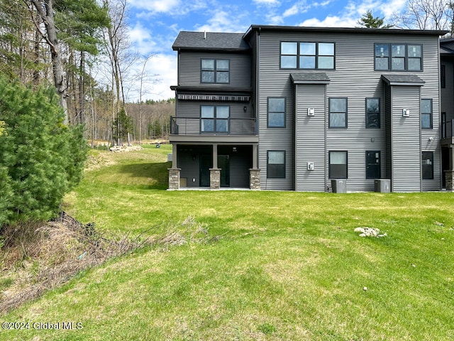 rear view of house with central AC unit and a lawn