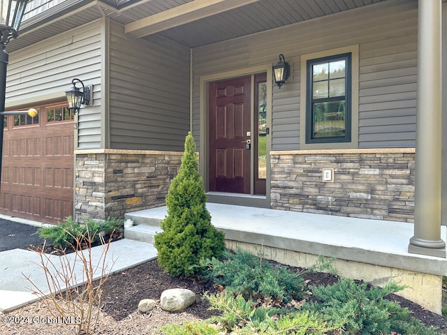 view of exterior entry featuring a garage and stone siding