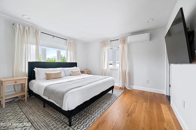 bedroom featuring a wall unit AC and light hardwood / wood-style flooring