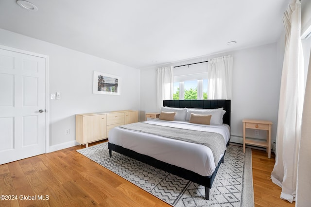 bedroom featuring light hardwood / wood-style floors and a baseboard heating unit