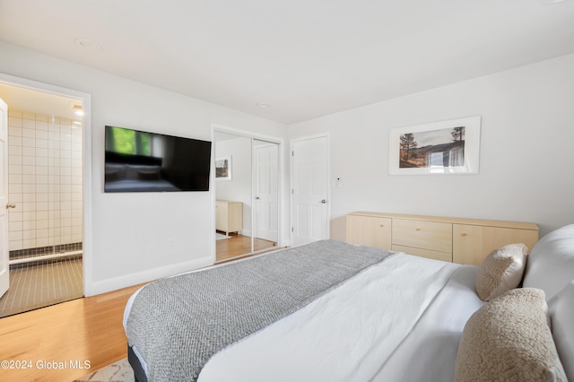 bedroom with light wood-type flooring, connected bathroom, and a closet