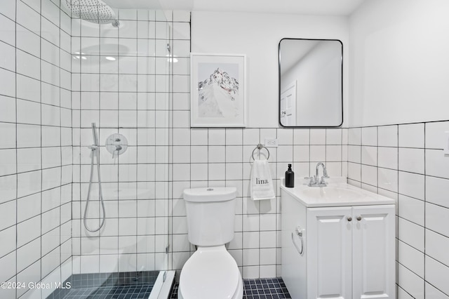 bathroom with toilet, vanity, tile walls, and tiled shower