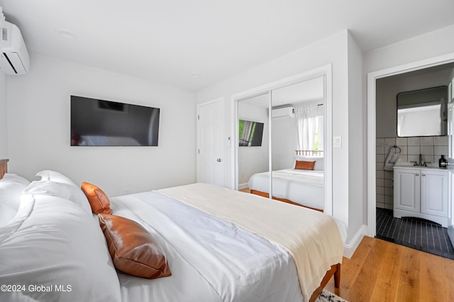 bedroom featuring sink, light hardwood / wood-style flooring, a wall mounted AC, and a closet