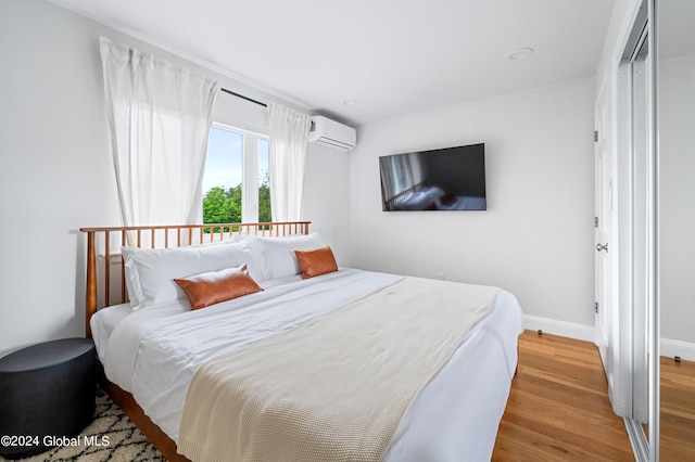 bedroom featuring a wall mounted air conditioner and light hardwood / wood-style flooring