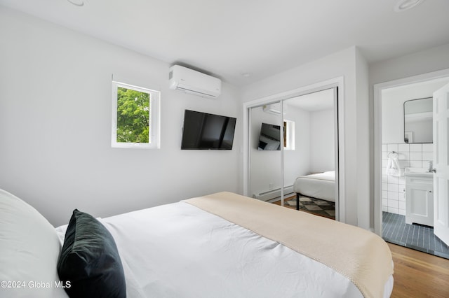 bedroom featuring light wood-type flooring, a wall mounted AC, a baseboard heating unit, sink, and a closet