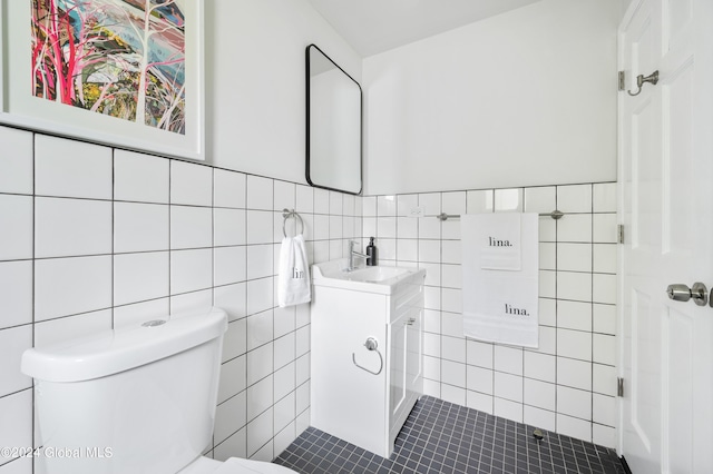 bathroom featuring toilet, vanity, tile patterned floors, and tile walls