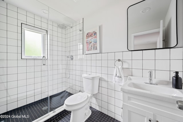 bathroom featuring vanity, tile patterned flooring, toilet, tile walls, and a shower with shower door