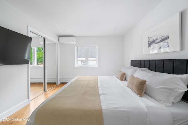 bedroom featuring a wall mounted air conditioner, hardwood / wood-style flooring, a baseboard radiator, and a closet