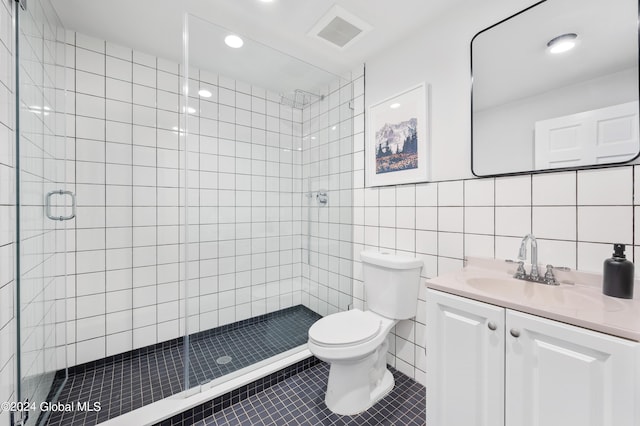 bathroom featuring vanity, tile patterned floors, toilet, tile walls, and walk in shower