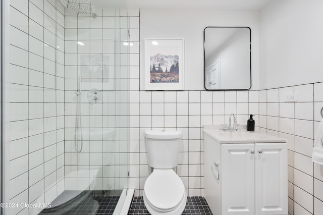 bathroom with vanity, tile patterned floors, toilet, tiled shower, and tile walls