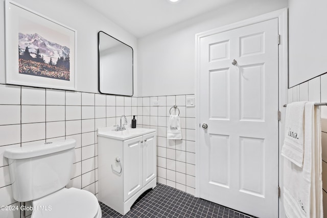 bathroom with tile patterned flooring, vanity, toilet, and tile walls