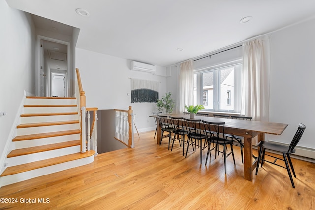 dining space featuring an AC wall unit and light wood-type flooring