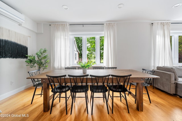 dining area featuring a healthy amount of sunlight, light wood-type flooring, and an AC wall unit