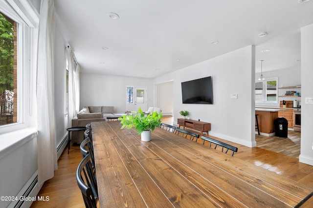 dining space featuring light hardwood / wood-style floors, a wealth of natural light, and a baseboard radiator