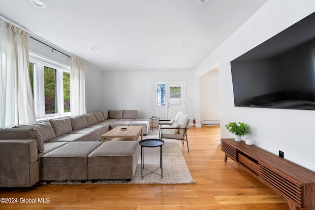 living room with baseboard heating and light hardwood / wood-style flooring