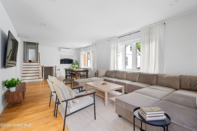 living room with a wall mounted air conditioner and light hardwood / wood-style floors