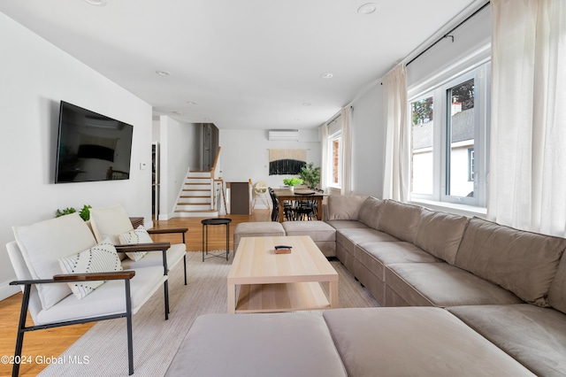 living room featuring a wall unit AC and light hardwood / wood-style flooring