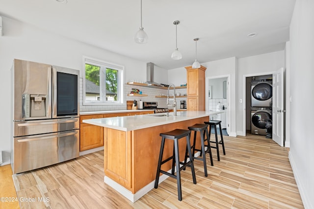 kitchen featuring appliances with stainless steel finishes, backsplash, a breakfast bar area, hanging light fixtures, and stacked washer / drying machine