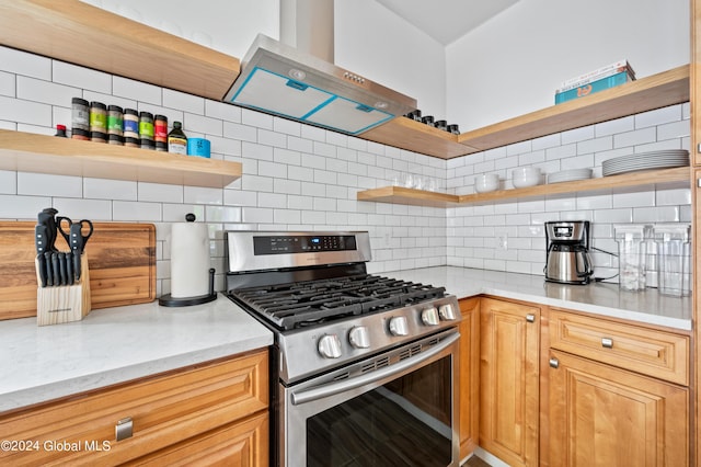 kitchen with tasteful backsplash, stainless steel range with gas cooktop, light stone counters, and wall chimney range hood