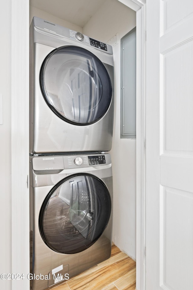 washroom with wood-type flooring and stacked washing maching and dryer