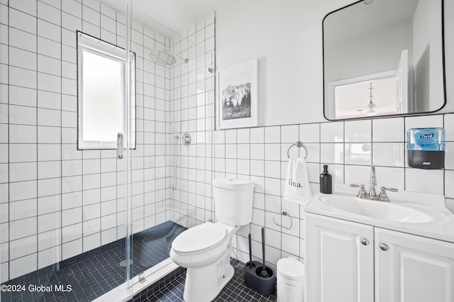 bathroom with vanity, a shower with door, tile patterned flooring, toilet, and tile walls