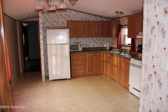 kitchen featuring lofted ceiling, sink, and white appliances