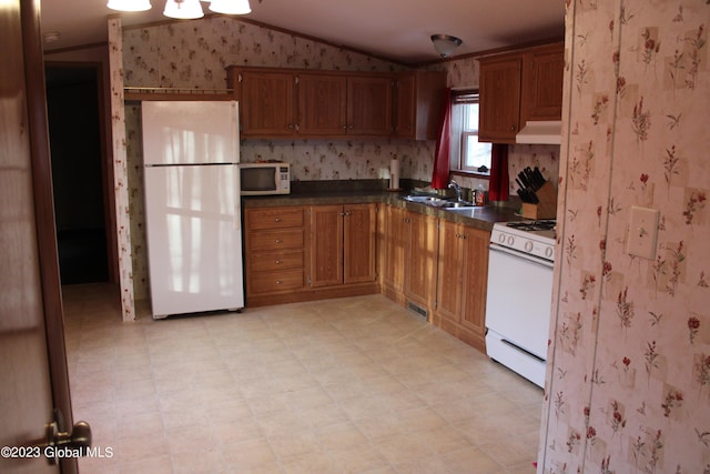 kitchen featuring vaulted ceiling, white appliances, and sink