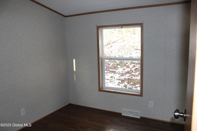 unfurnished room featuring dark wood-type flooring and ornamental molding