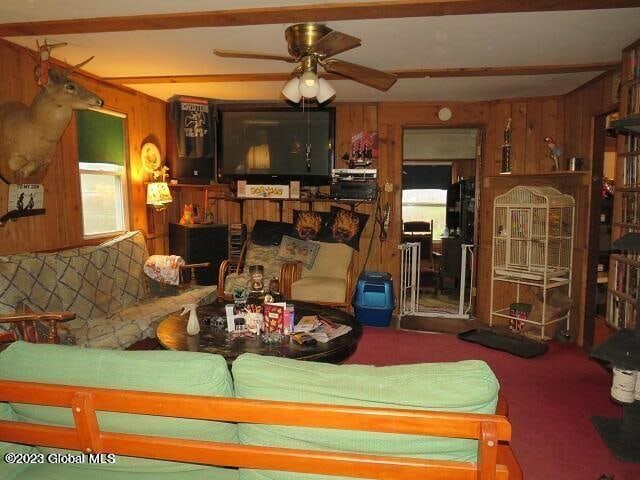 living room featuring carpet, wood walls, and ceiling fan