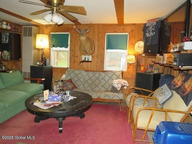 carpeted living room with wood walls and ceiling fan