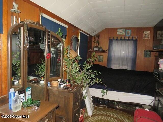 bedroom featuring lofted ceiling and wood walls