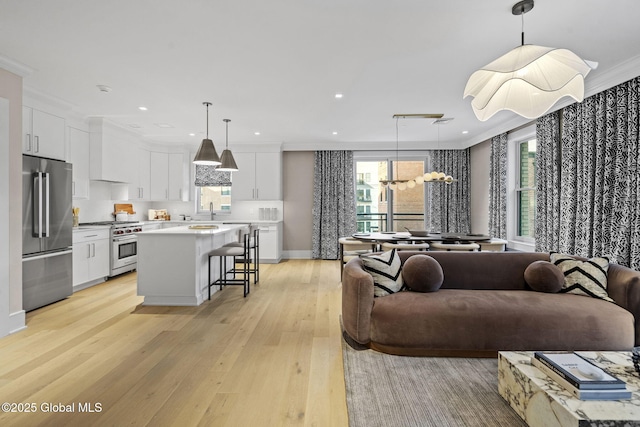 living room with recessed lighting, an inviting chandelier, light wood-style floors, and ornamental molding