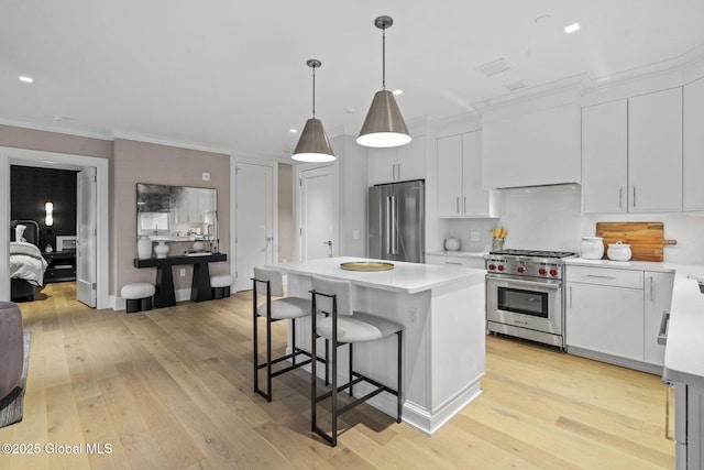 kitchen with premium appliances, light wood-style floors, a breakfast bar area, and light countertops