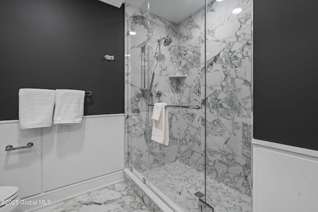 bathroom with a marble finish shower, toilet, marble finish floor, and wainscoting