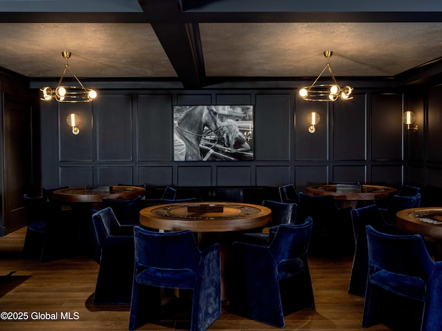 playroom with wood finished floors, coffered ceiling, beam ceiling, a decorative wall, and a chandelier