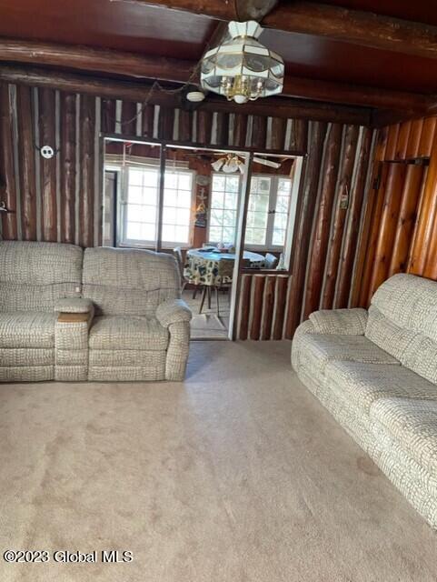 carpeted living area featuring beamed ceiling