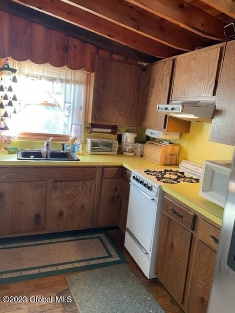 kitchen with sink, exhaust hood, and white gas range