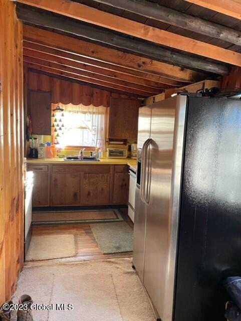 kitchen featuring lofted ceiling with beams, sink, and stainless steel fridge with ice dispenser