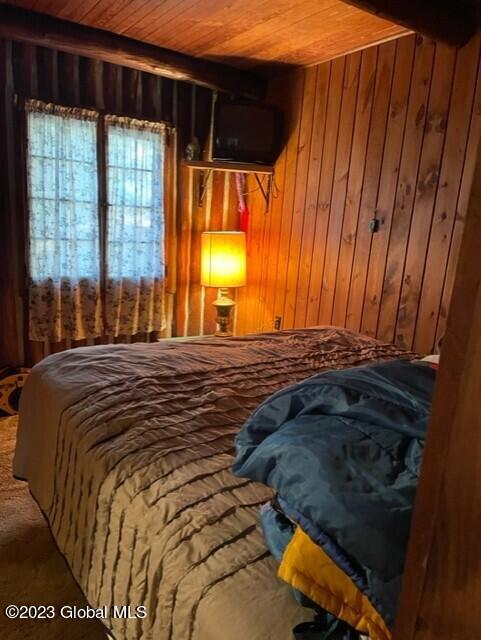 carpeted bedroom featuring wood walls and wood ceiling