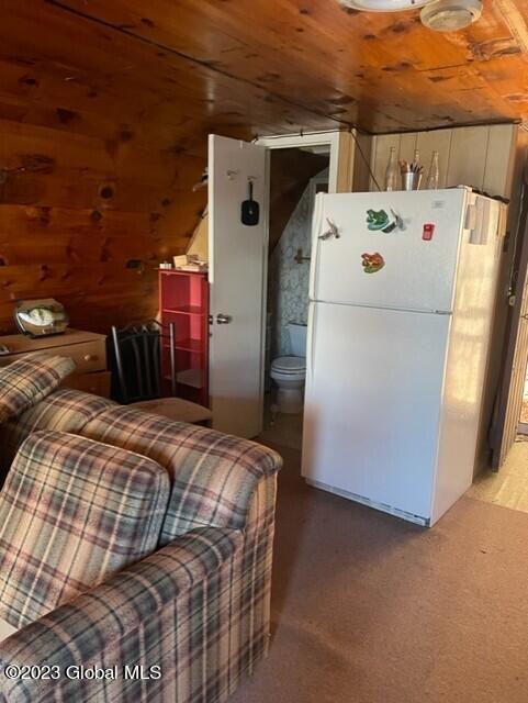 carpeted bedroom with white fridge, connected bathroom, lofted ceiling, and wooden ceiling