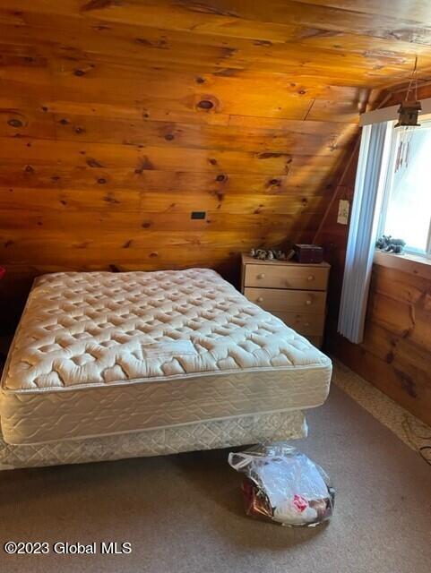 unfurnished bedroom featuring carpet floors, lofted ceiling, and wood ceiling