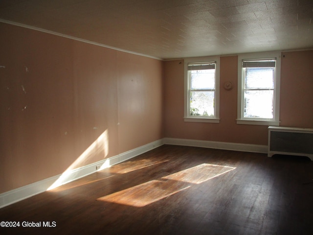 empty room with ornamental molding, dark hardwood / wood-style flooring, and radiator